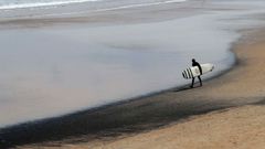 Un surfista transporta su tabla en la playa de San Lorenzo de Gij�n. ARCHIVO