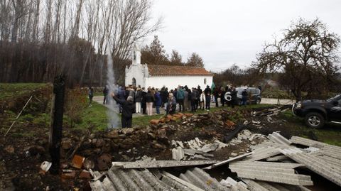 Los vecinos durante la procesin junto a la capilla, y en primer plano los restos de un almacn destruido por el incendio de hace dos meses