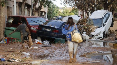 Varias personas caminan entre el lodo acumulado en las calles a causa de las intensas lluvias cadas