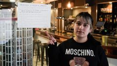 Jenny, propietaria de la cafeter�a Gabana, con el cartel en el que proh�be la entrada a personas conflictivas