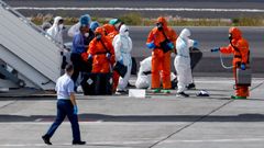Personal con EPI desinfecta a los pasajeros en la pista antes de que aborden el vuelo desde el aeropuerto Tenerife Sur.