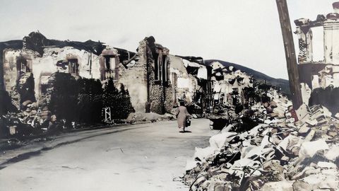 Oviedo, 1937.  Una mujer camina entre las ruinas de la calle Arzobispo Guisasola, devastada por la guerra