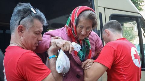Voluntarios de la Cruz Roja ayudan a una anciana evacuada de Kupiansk-Vuzlovyi