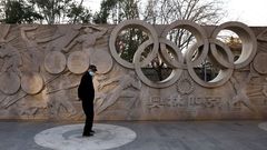Un hombre pasa por un relieve dedicado a los anillos ol�mpicos en un parque de Pek�n.