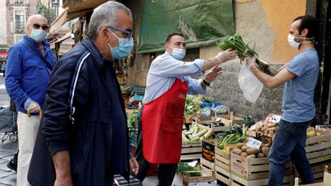 En Catania, Italia, los acuden a los mercados ataviados con mascarilla, igual que los vendedores