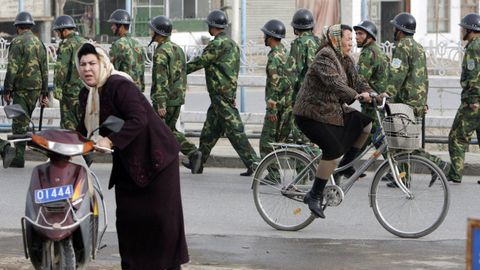Mujeres Uigures pasan junto a soldados chinos en una calle de Yecheng, en la regi�n china de Xinjiang