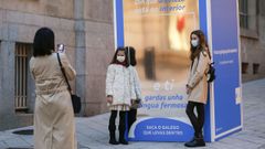 Una mujer fotograf�a a dos ni�as con mascarilla en la R�a do Paseo de Ourense