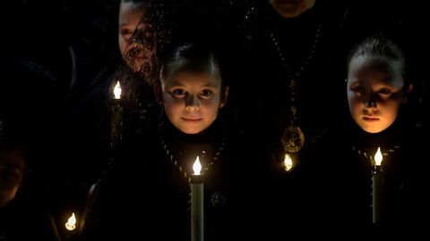 Los penitentes rezan después de que la Procesión del Santo Encuentro fuese suspendida por la lluvia, en Avilés