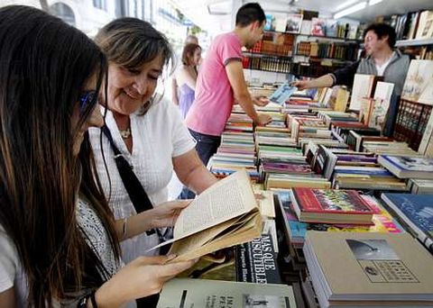 Dos lectoras examinan un ejemplar en la Feria del Libro Antiguo y de Ocasi�n en la Alameda.