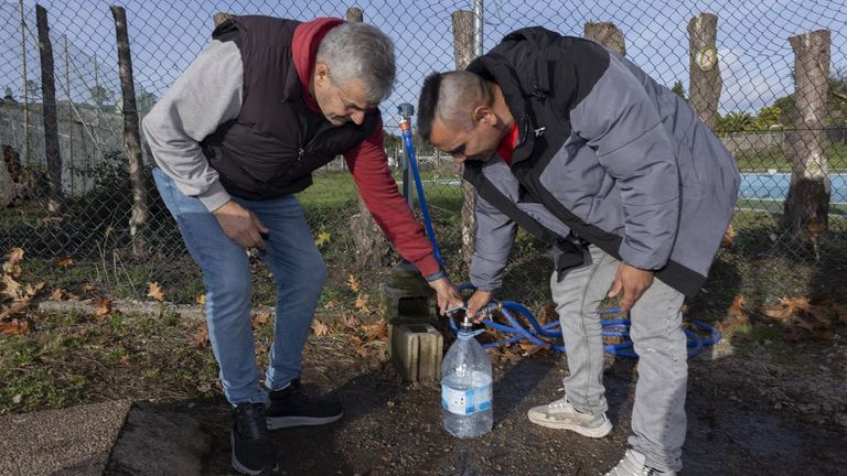 Dos vecinos de la urbanizaci�n privada de monte Xalo llenan una garrafa de agua de un manantial pr�ximo al campo de f�tbol de O Castelo.