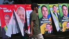 Un hombre camina ante carteles de los dos principales candidatos a las elecciones presidenciales de Brasil, Lula da Silva y Fl�vio Bolsonaro, en Brasilia