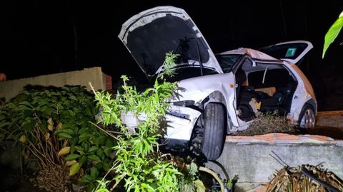 Uno de los coches implicados en el accidente acab tirando y subido encima del cierre de ladrillo de una vivienda