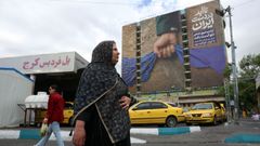Una mujer pasea por Teher�n con una cartelera de fondo que refleja el cierre por parte de Ir�n del estrecho de Ormuz.
