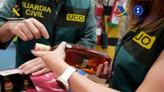 Agentes de la UCO con botellas de alcohol intervenidas durante el operativo contra la red fraudulenta