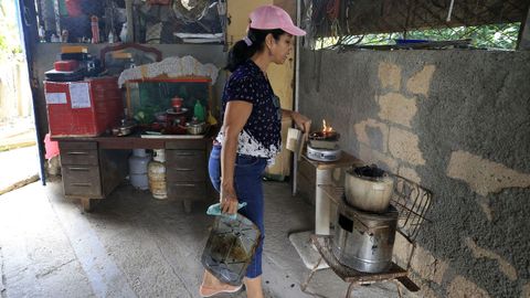 Una mujer cocina en dos hornillos de carb�n en una vivienda de La Habana.