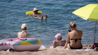 Grupo de personas en la playa tomando el sol y disfrutando del agua