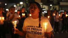  Una mujer sostiene velas durante una vigilia afuera del centro penitenciario Rodeo I este viernes, en el municipio Zamora estado Miranda (Venezuela).