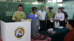 Funcionarios y voluntarios de la Comisi�n Electoral de la Uni�n revisan la m�quina de votaci�n electr�nica en un colegio electoral, un d�a antes de las elecciones generales en Yang�n, Myanmar.