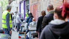 Vecinos realizan una cola para recoger bolsas de la Asociaci�n de Vecinos Parque Aluche (Madrid) donde los voluntarios han entregado alimentos y productos donados en su sede ubicada en la calle Quero n� 69 a aquellas personas que lo necesitan