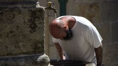 Un hombre se refresca en una fuente, en Combarro. 