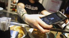 Personal de una cafeter�a cobrando con un dat�fono a un cliente.