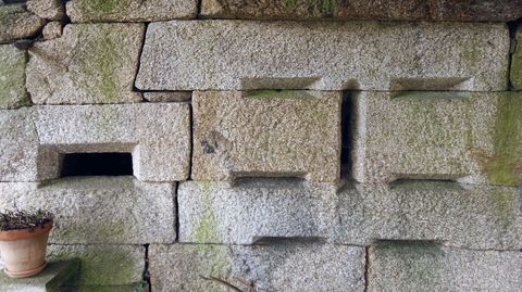 Ocos de ventilación na parte baixa dunha casa, probablemente para airear unha despensa de produtos da matanza