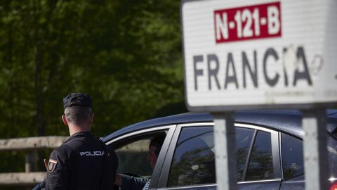 Un cartel se�ala la direcci�n a Francia mientras un polic�a interroga a un conductor en un control en la frontera navarro-francesa.