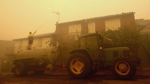 Un vecino remoja el tejado de una casa con una manguera acoplada a una cisterna agrcola