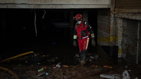 Un bombero revisa un garaje inundado por la dana en Benetússer (Valencia)