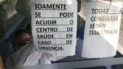 Una trabajadora sanitaria coloca los carteles a la entrada del ambulatorio de A Barrela
