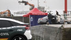 El coche que acab en el mar, al fondo de la imagen, inspeccionado por agentes.