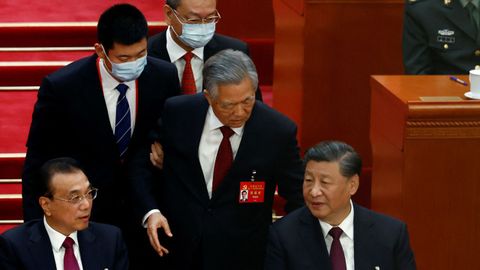 Hu Jintao se resiste y el bedel lo sujeta por el brazo, pero mientras abandona la sala le dice algo a Xi Jinping, quien le contesta sin apenas girarse