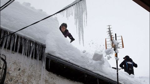  Vecinos de Pajares (Asturias) retiran nieve del tejado de su casa de 300 aos, una de las ms antiguas del pueblo.