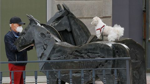 Un hombre fotografa a su perro subido a la escultura urbana conocida como Asturcones, en el centro de Oviedo, este sbado. 