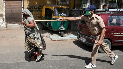 Un polica usa su bastn para presionar a una residente que infringe las reglas en una ciudad de La India