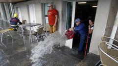 Los propietarios del N�mero 6 sacan agua de su negocio con un cubo tras una inundaci�n el 2 de junio del 2020. La de este 29 de mayo fue mucho peor
