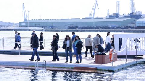 Ciudadanos en la nueva plataforma para baistas instalada en O Parrote; al fondo, el muelle de San Diego