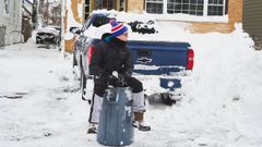 Un hombre, sentado ante una vivienda cubierta de nieve en la ciudad de Buffalo (Nueva York)