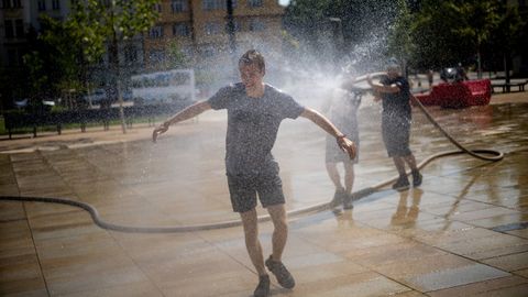 Una persona se refresca con una manguera en una plaza de Praga.