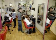 Qunwei Huang, propietario de la peluquer�a S. M. de la avenida Finisterre, peina a una clienta. 