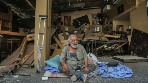 Un hombre se sienta en la acera enfrente de un bar destruido por la explosin