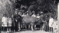 Una mujer posa con la vaca que sus hijos (elegantemente ataviados al estilo americano) le regalaron a su regreso de Cuba