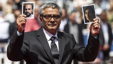 Mohammad Rasoulof mostrando fotografias de Missagh Zareh y Soheila Golestani a su llegada a Cannes  