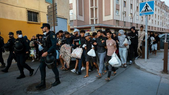 Centenares de personas se trasladan a pie durante el dispositivo de reubicaci�n de inmigrantes hasta un nuevo centro temporal, en el barrio de Los Rosales, en Ceuta.