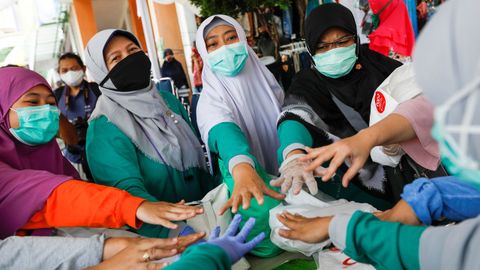 Un grupo de sanitarias indonesias se anima, antes de comenzar a realizar su trabajo en un mercado de Bogor