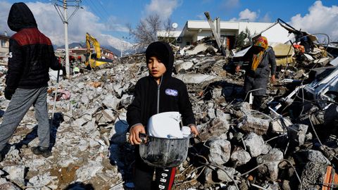 Un ni�o recoge utensilios de su vivienda derribada por el terremoto en Gaziantep