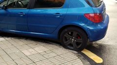 Un autom�vil con una de las ruedas pinchadas, en el barrio de El Natahoyo de Gij�n