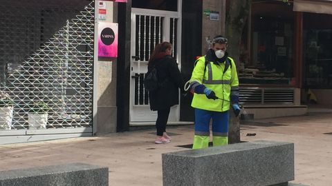 Trabajadores municipales desinfectando bancos, portales y otras zonas pblicas de Ourense