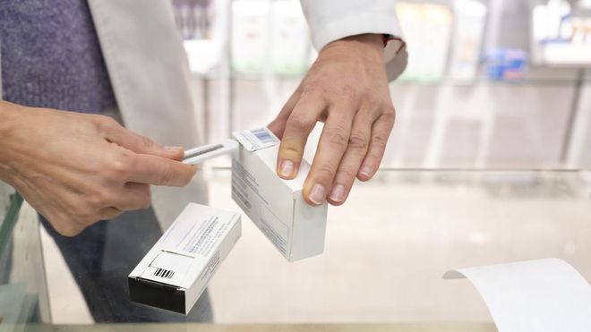 Un farmac�utico corta con un c�ter el cup�n de los f�rmacos