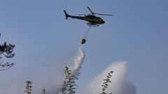 Helic�ptero de Medio Rural descargando agua para sofocar las llamas junto a un grupo de viviendas de O Sisto, Carballo